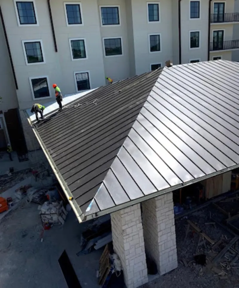 Crew installing standing seam metal roof panels on a commercial project in Lenoir